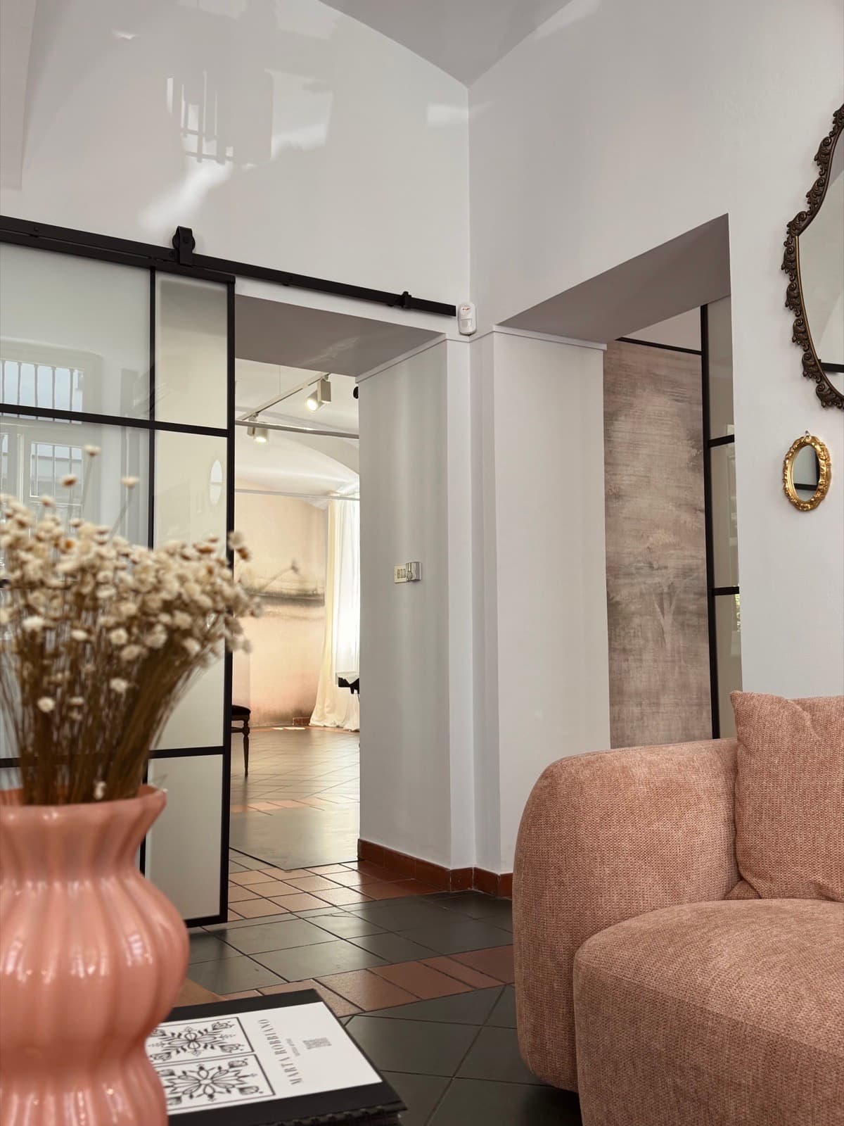 Il salotto d'ingresso di 707 Studio: poltrona, fiori secchi e la porta a vetri che porta verso le sale.
